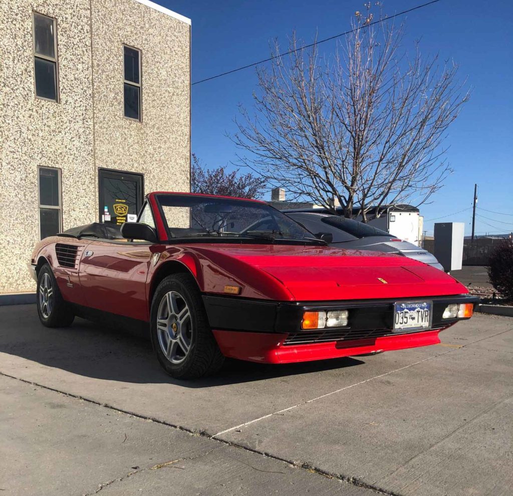 Red vintage car parked outside DE Performance LLC auto repair shop